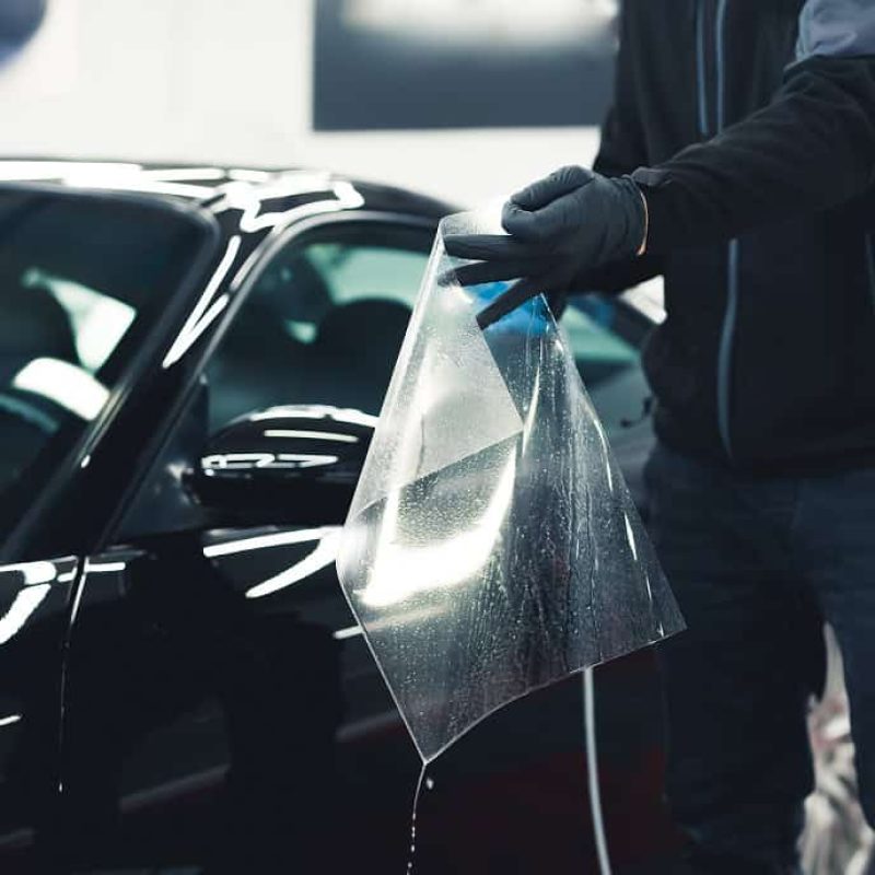 man-wearing-black-gloves-preparing-sheet-ppf-paint-protection-film-before-applying-it-side-car